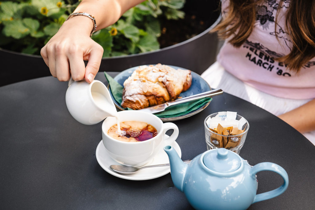 A person pours milk into a cup of tea served at the Philanthropist Cafe in Tunbridge Wells