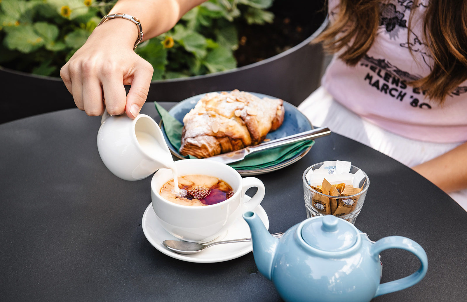 A person pours milk into a cup of tea served at the Philanthropist Cafe in Tunbridge Wells