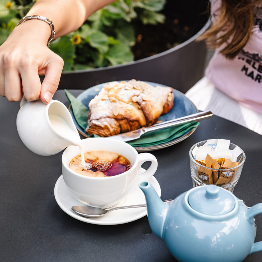 A person pours milk into a cup of tea served at the Philanthropist Cafe in Tunbridge Wells